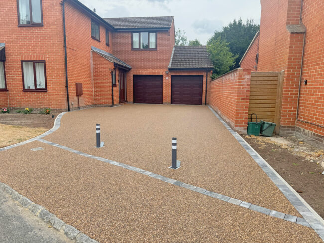 Large resin driveway going up to garage with bollards