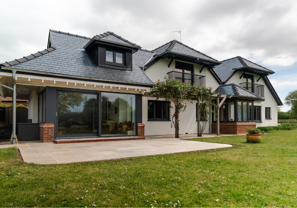 Ridge Porcelain Patio, Crowmarsh, Feature Image A spacious house featuring a large porcelain patio and expansive lawn, surrounded by greenery.
