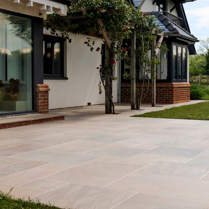 A spacious porcelain patio mimicking sandstone, showcasing a large stone floor and an expansive window.