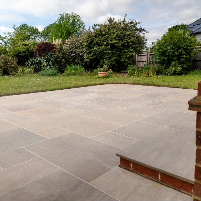 A large porcelain patio in Sunset Gold resembling sandstone, featuring a step and brick walls.